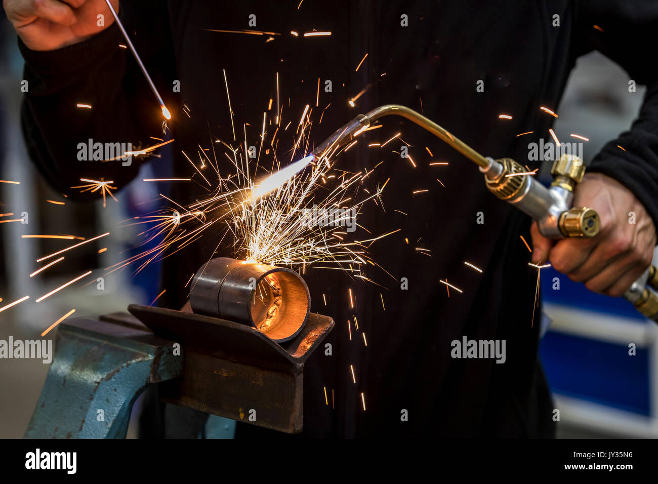 Welding, with a welding torch two metal pipes are welded, training workshop for heating and plumbing craftsmen, Stock Photo