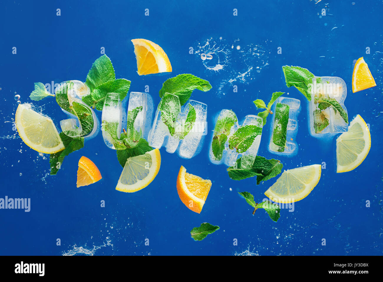 Ice cube lettering with frozen mint leaves, lemon slices and oranges on a blue background with water splashes. Text says Summer Stock Photo