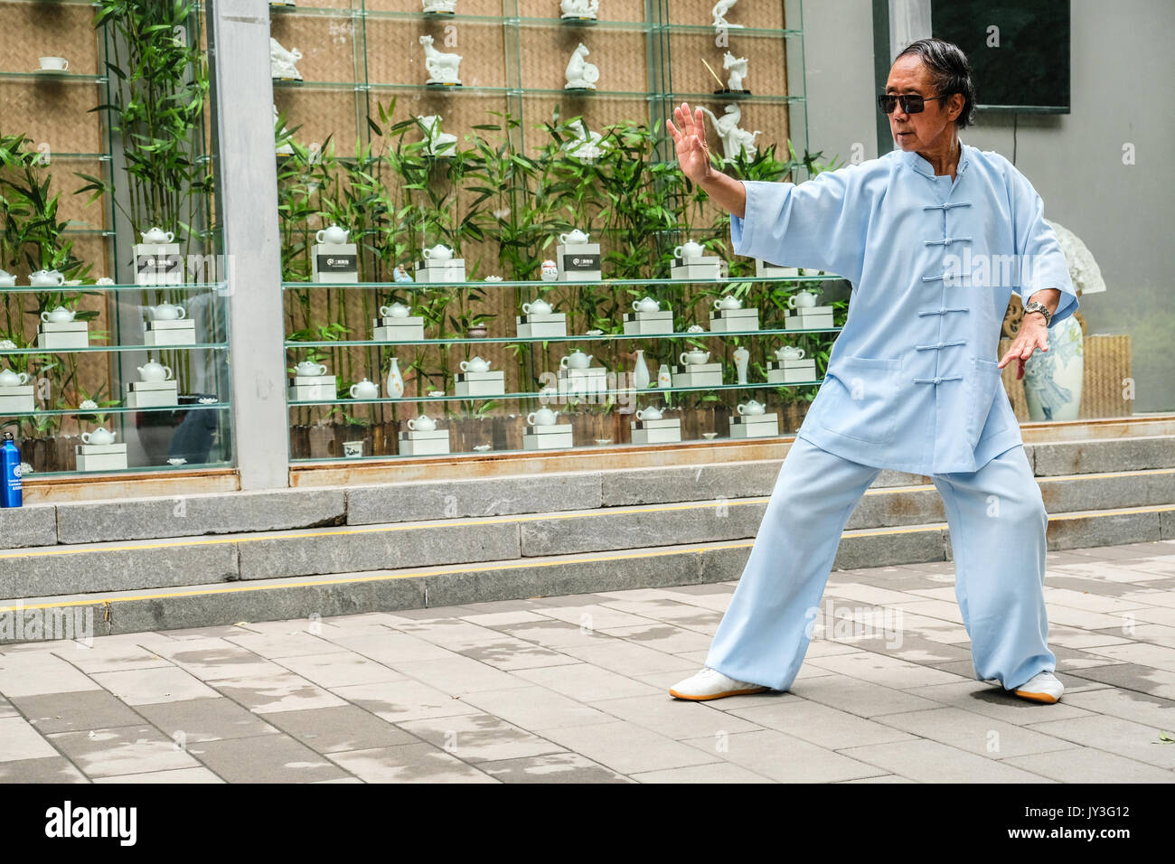 A Chinese man in traditional Chinese dressing practicing Tai Ji at Yu Yuan Tan park in Beijing, China Stock Photo