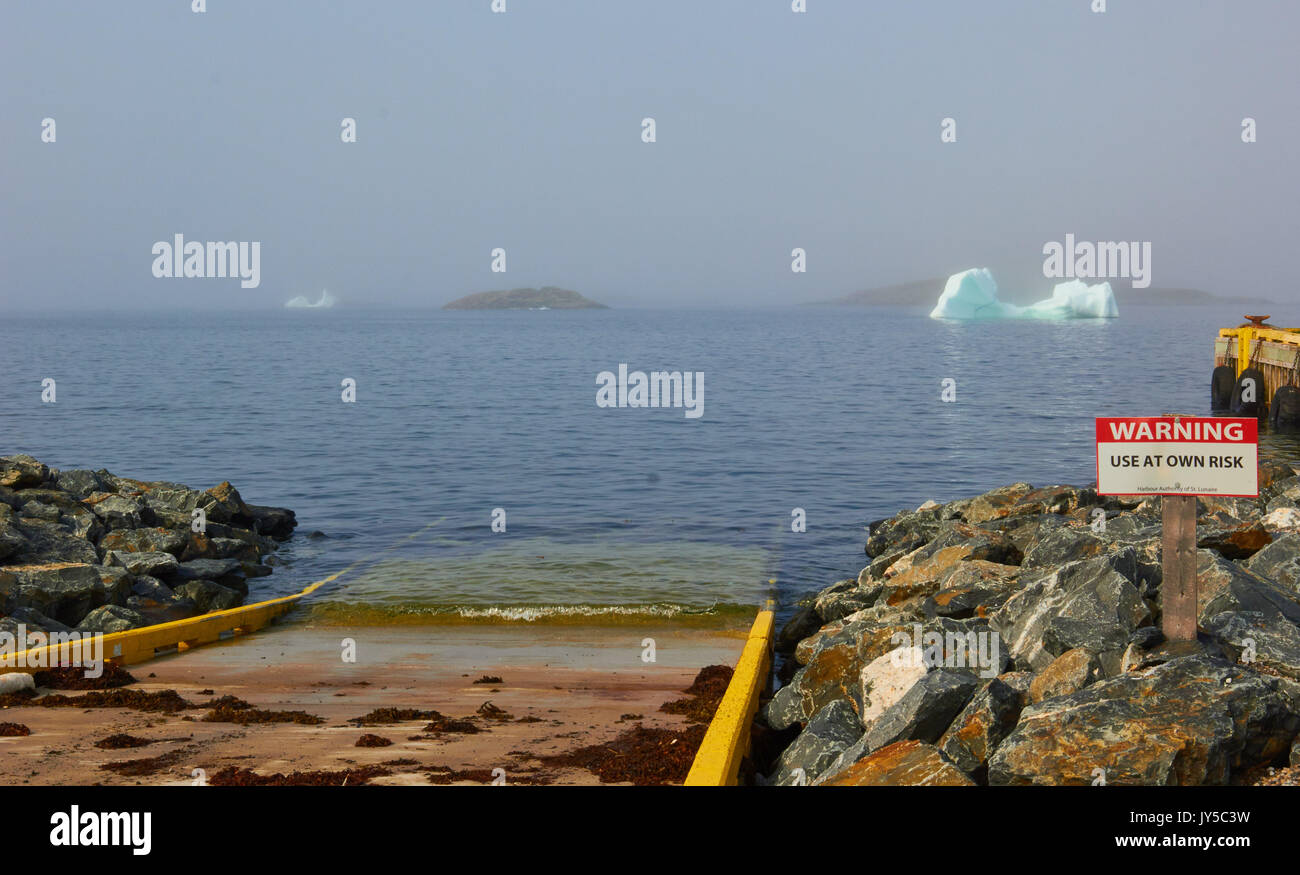 Warning sign and icebergs in summer mist, St. Lunaire-Griquet at the northern tip of the Great Northern Peninsula, Newfoundland, Canada Stock Photo