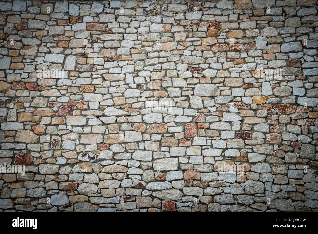 Stone wall background of colorful stones with vignetted borders Stock