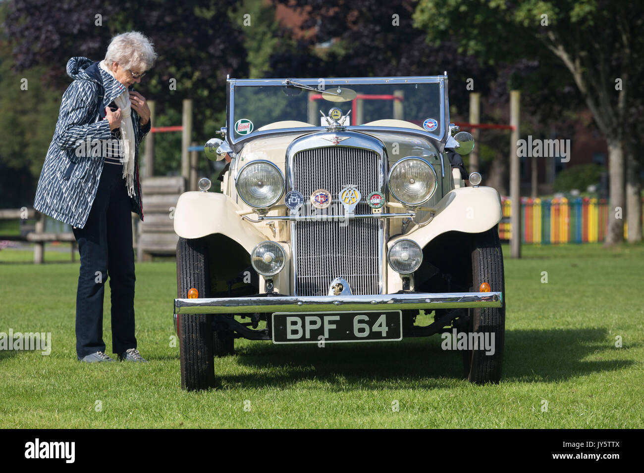 Woman at classic vintage car rally next to open-top vehicle Stock Photo