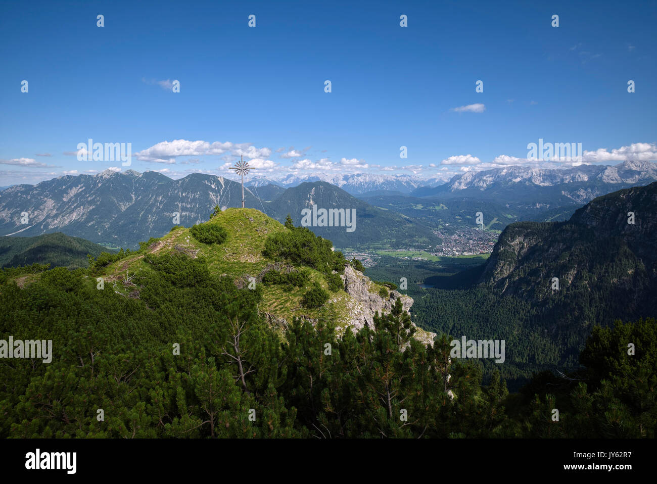 view of cross at Bruenstlkreuz mountain summit and Garmisch-Partenkirchen in the valley, Bavaria, Germany Stock Photo