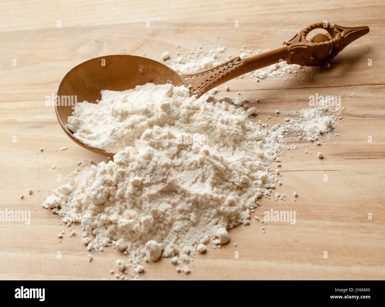 old carved wood spoon with wheat flour on the kitchen table Stock Photo