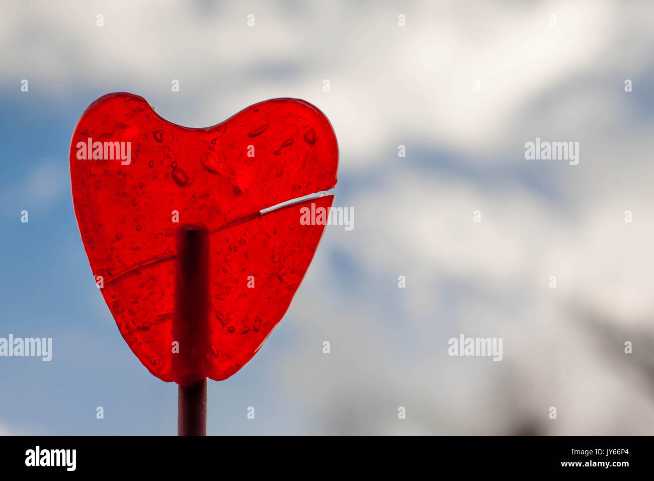 Lollipop candy with heart shape in blue skyl background Stock Photo