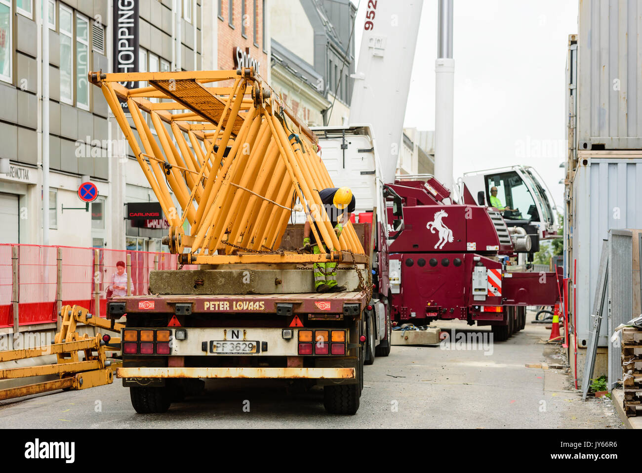 Kristiansand, Norway - August 1, 2017: Documentary of everyday life in the city. Construction worker securing crane parts on truck for transport. Mobi Stock Photo
