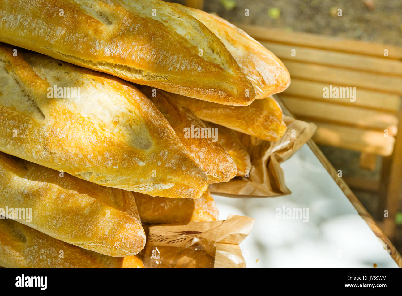 Pile of freshly baked rustic French baguettes on garden table, wooden ...