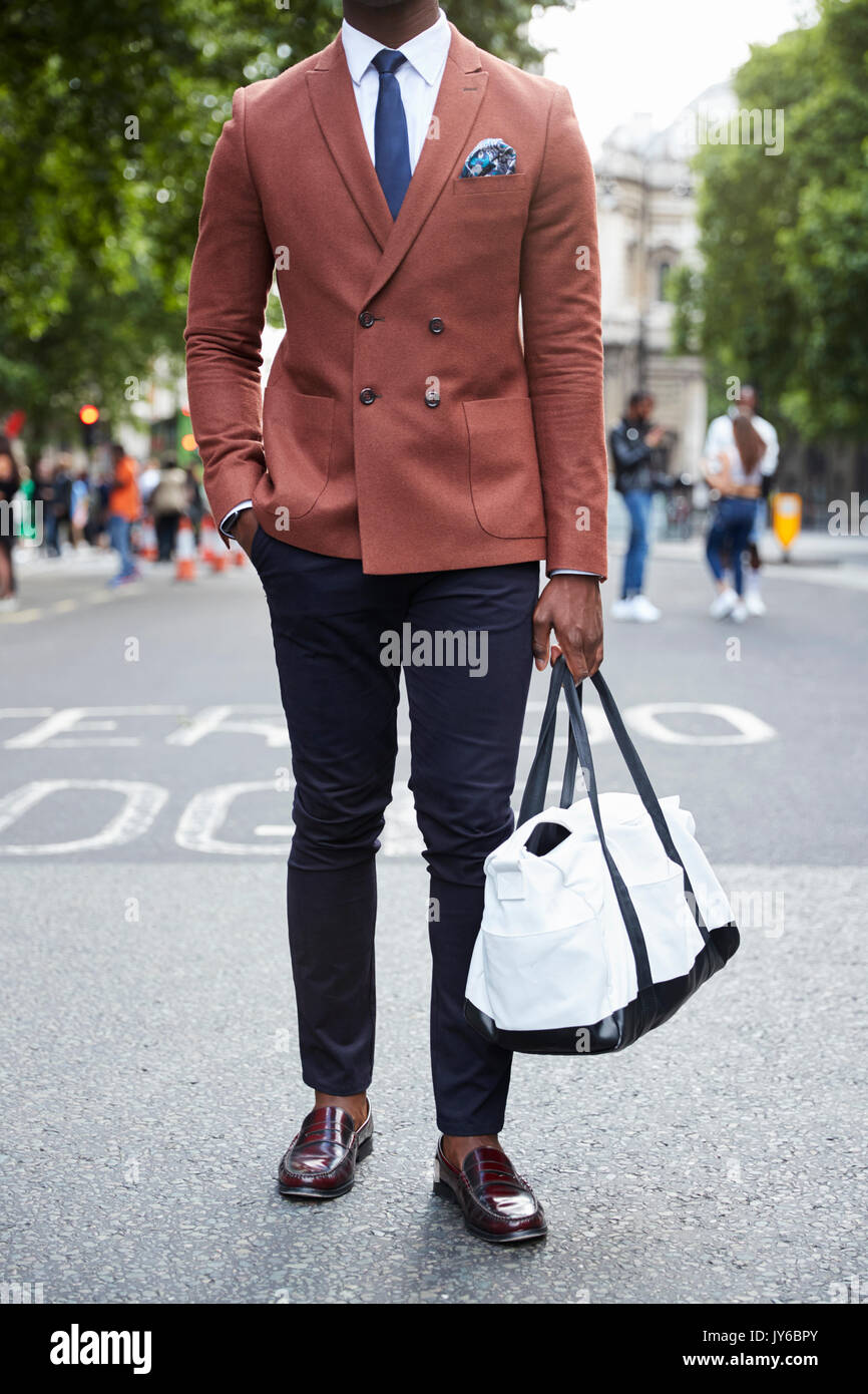 Low section of man in salmon jacket and tie carrying holdall Stock Photo -  Alamy