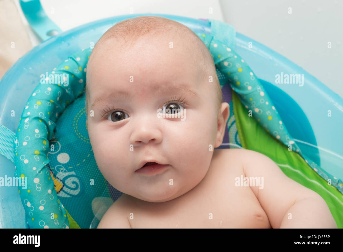 Portrait of a cute baby boy sitting in bath. Adorable seven month old