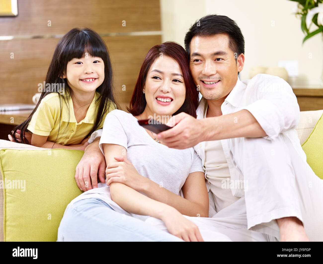 asian mother father and daughter watching TV at home. Stock Photo