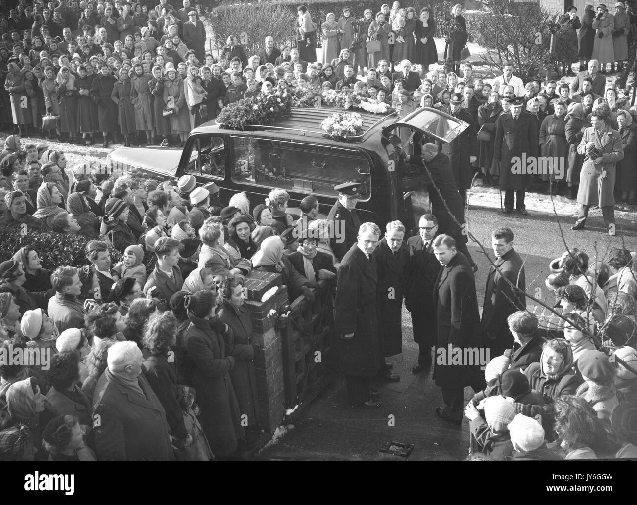 Three of Duncan Edwards's former England teammates stand in a solemn group as the coffin is placed in the hearse at the funeral of the young Manchester United and England half-back at Dudley. In the small group outside the church are the pallbearers England and Wolves captain Billy Wright (fourth from left), Ray Barlow (second from left) and Don Howe (r) - both of West Bromwich Albion. Stock Photo