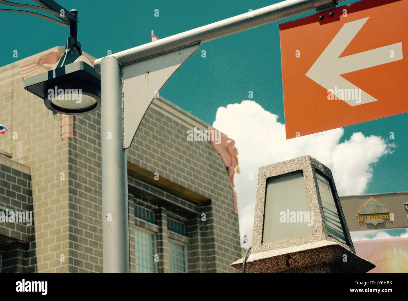 White arrow sign on orange label with building background Stock Photo