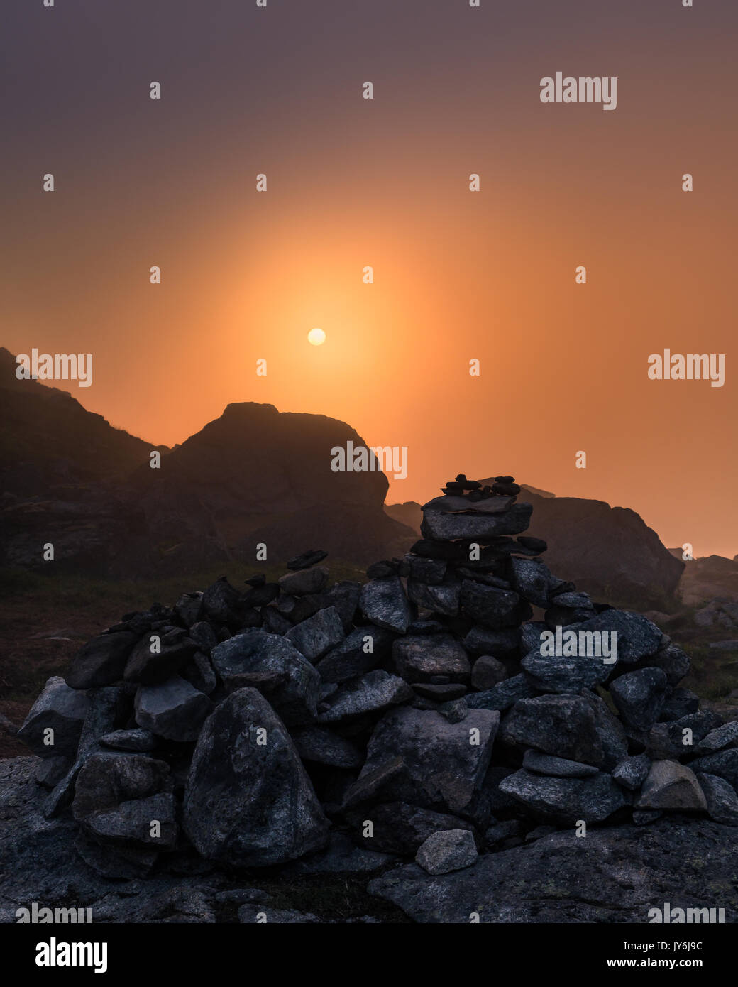 Sunlight comes through the fog at summer night in top of the mountain, Lofoten, Norway Stock Photo