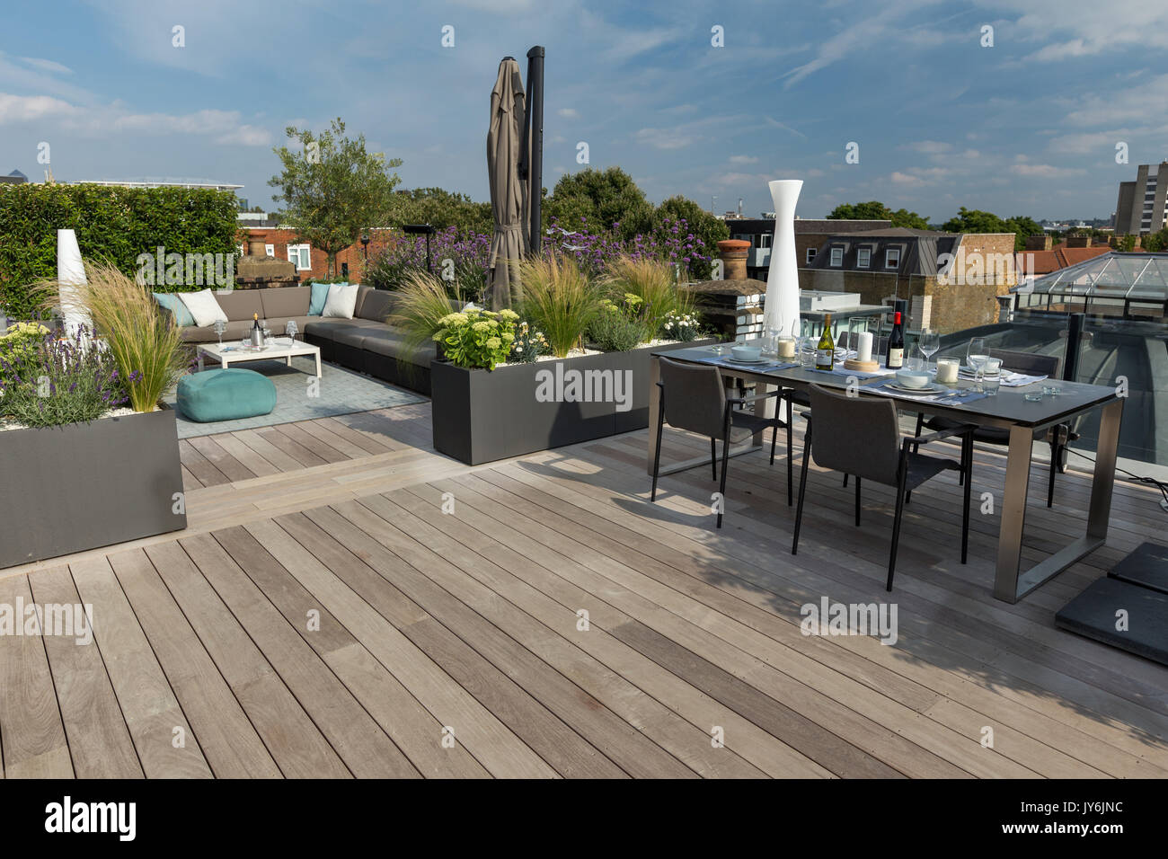 Luxurious roof terrace in London with hardwood timber decking, contemporary planters with lush planting and modern outdoor furniture Stock Photo