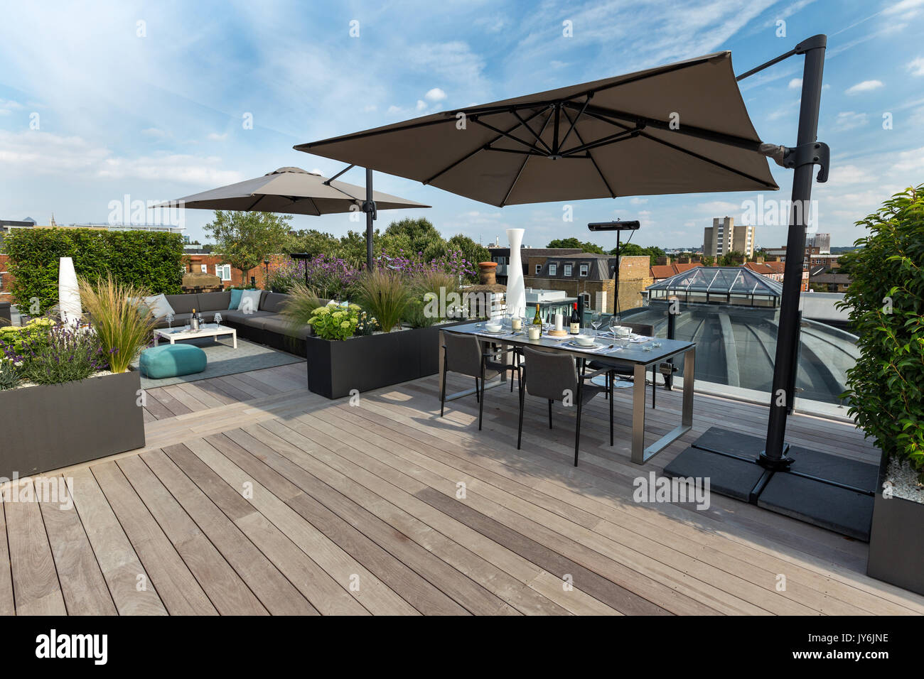 Luxurious roof terrace in London with hardwood timber decking, contemporary planters with lush planting and modern outdoor furniture Stock Photo