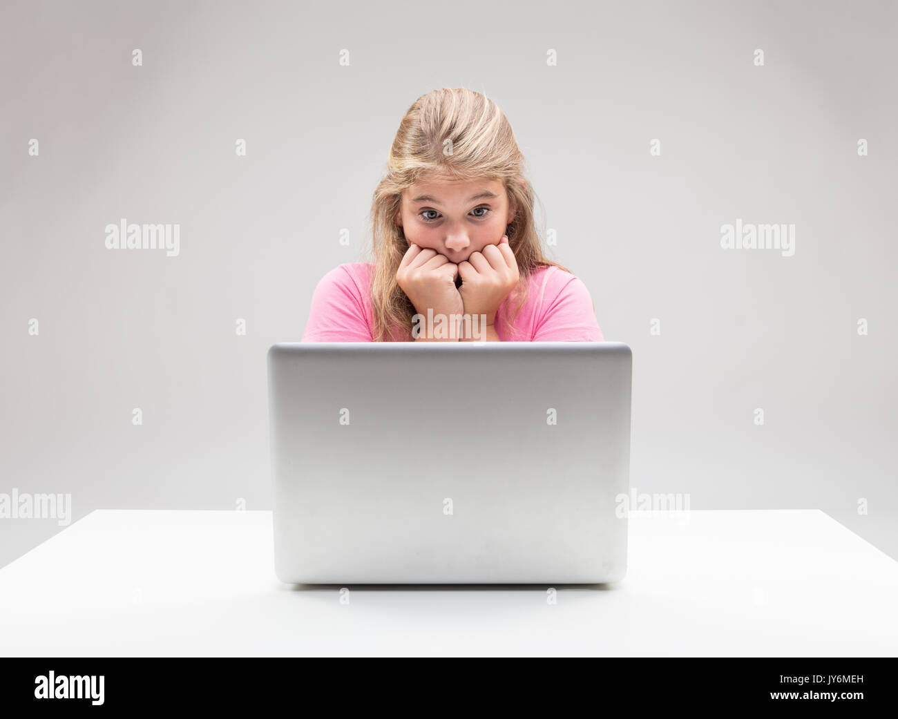 little girl frightened by something happening on her laptop computer ...