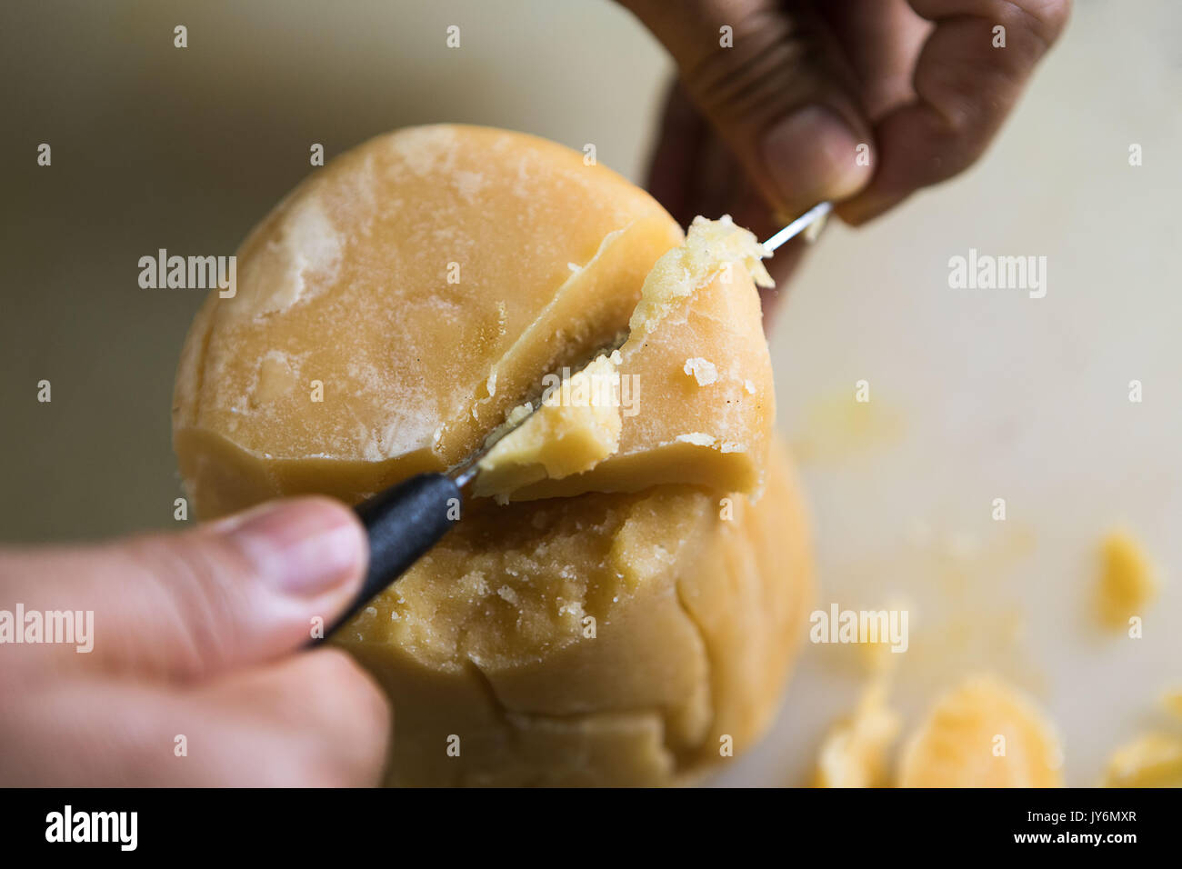 close up of adult male hands holding a knife with both hands and cutting jaggery block Stock Photo