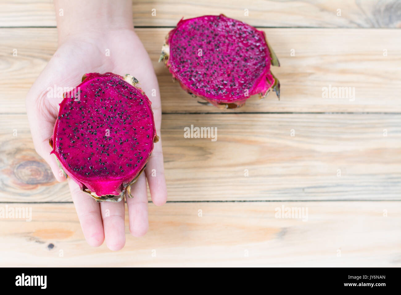 Red  dragon fruit in hand on wooden background Stock Photo