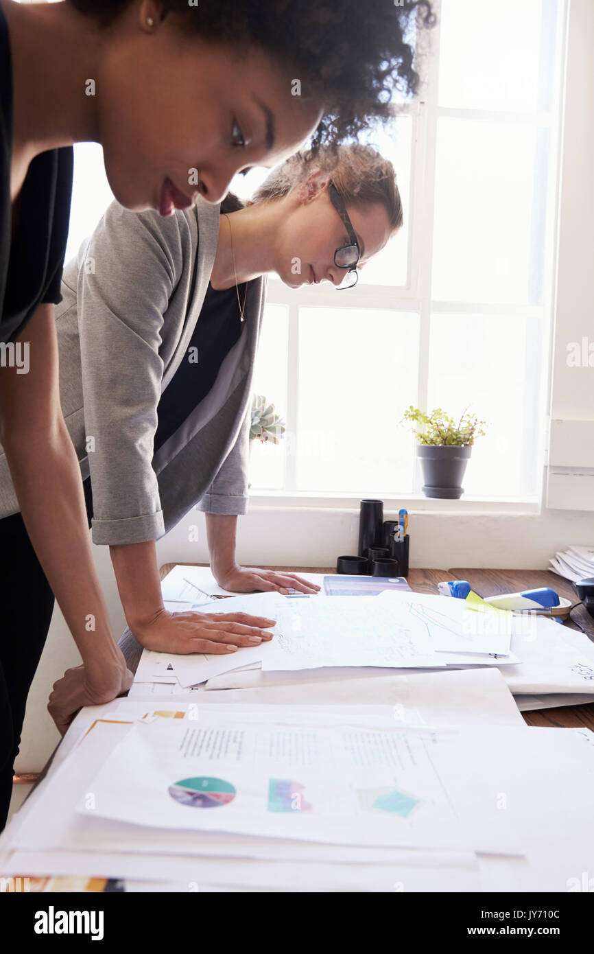 Two businesswomen studying documents in an office, vertical Stock Photo