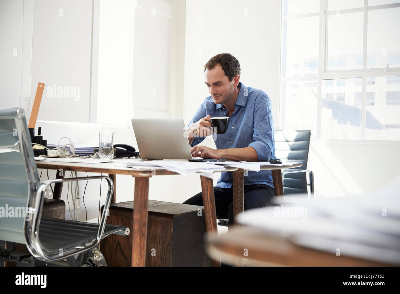 Young businessman using laptop computer and drinking coffee Stock Photo