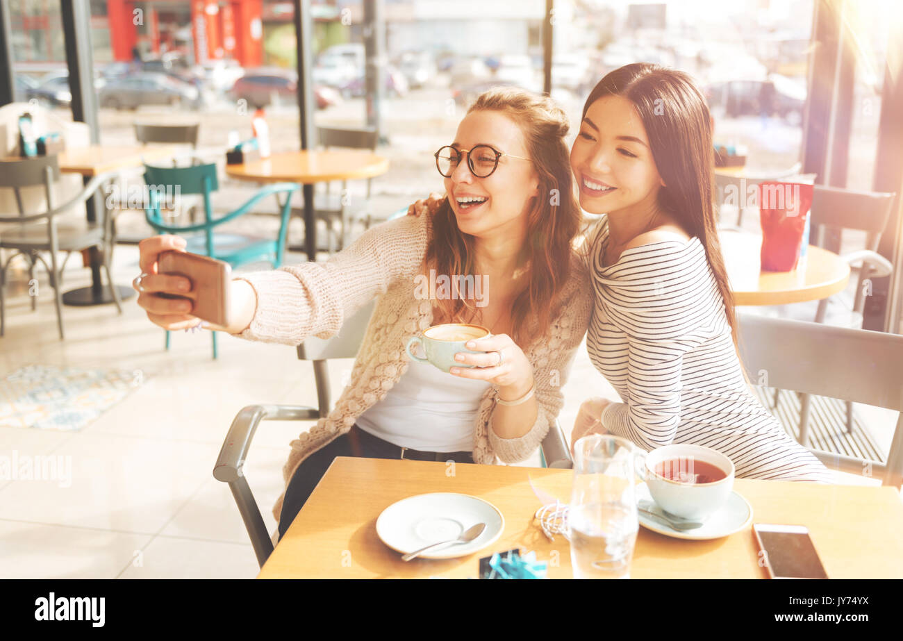 Positive young women making selfies together Stock Photo