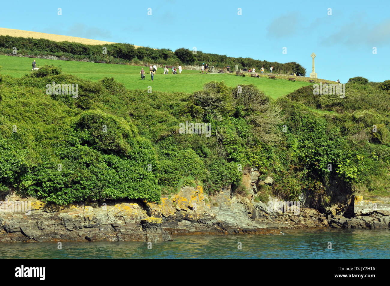 Visitors and tourists walking along the top of the cliffs and coastal footpaths at Padstow in north cornwall on a bright sunny day with camel river. Stock Photo