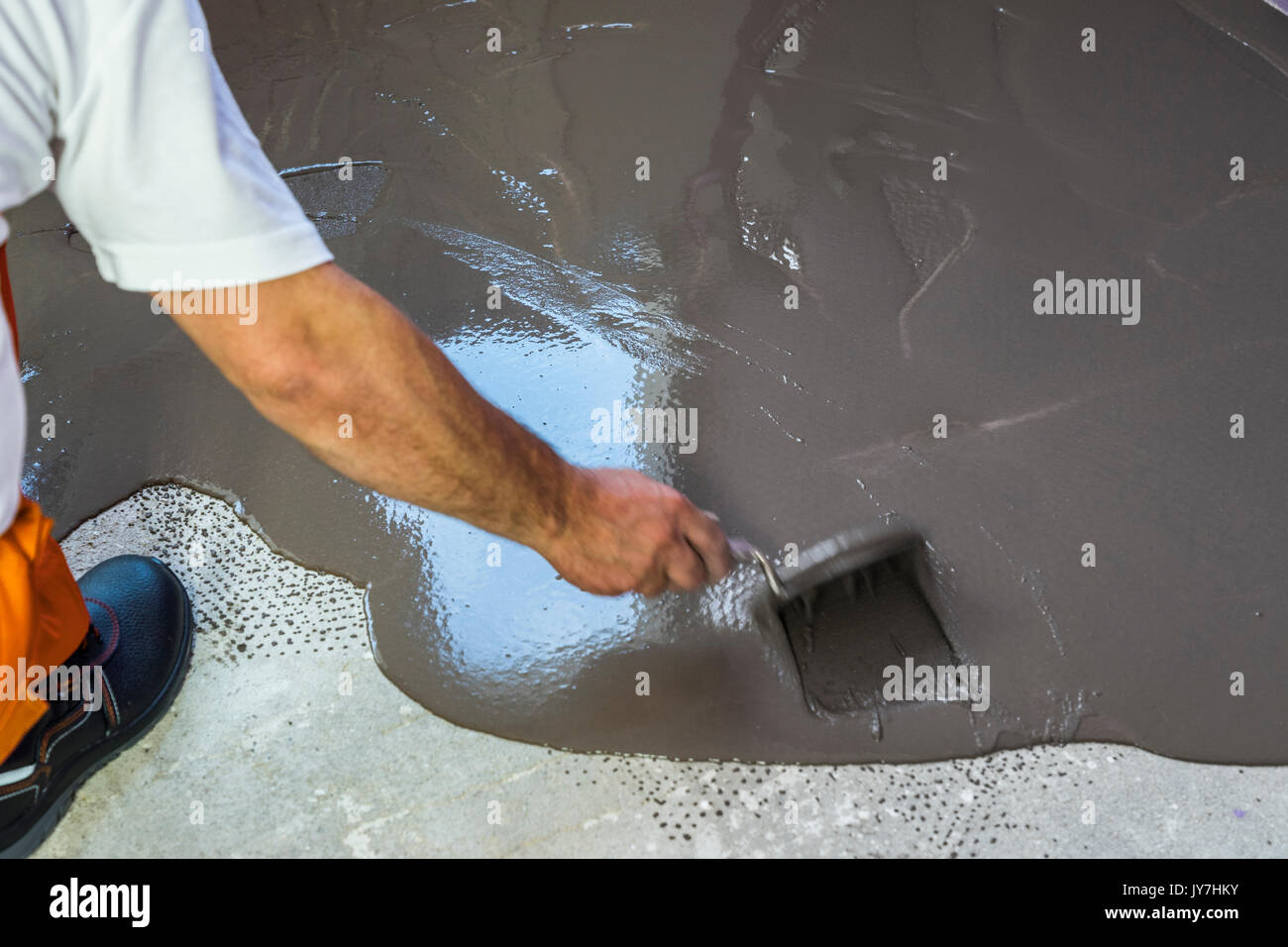 Worker Puts A Self Leveling Screed On Cement Floor In Apartment