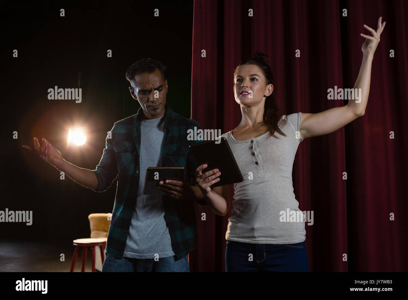 Actors rehearsing on stage while using digital tablet in theatre Stock Photo