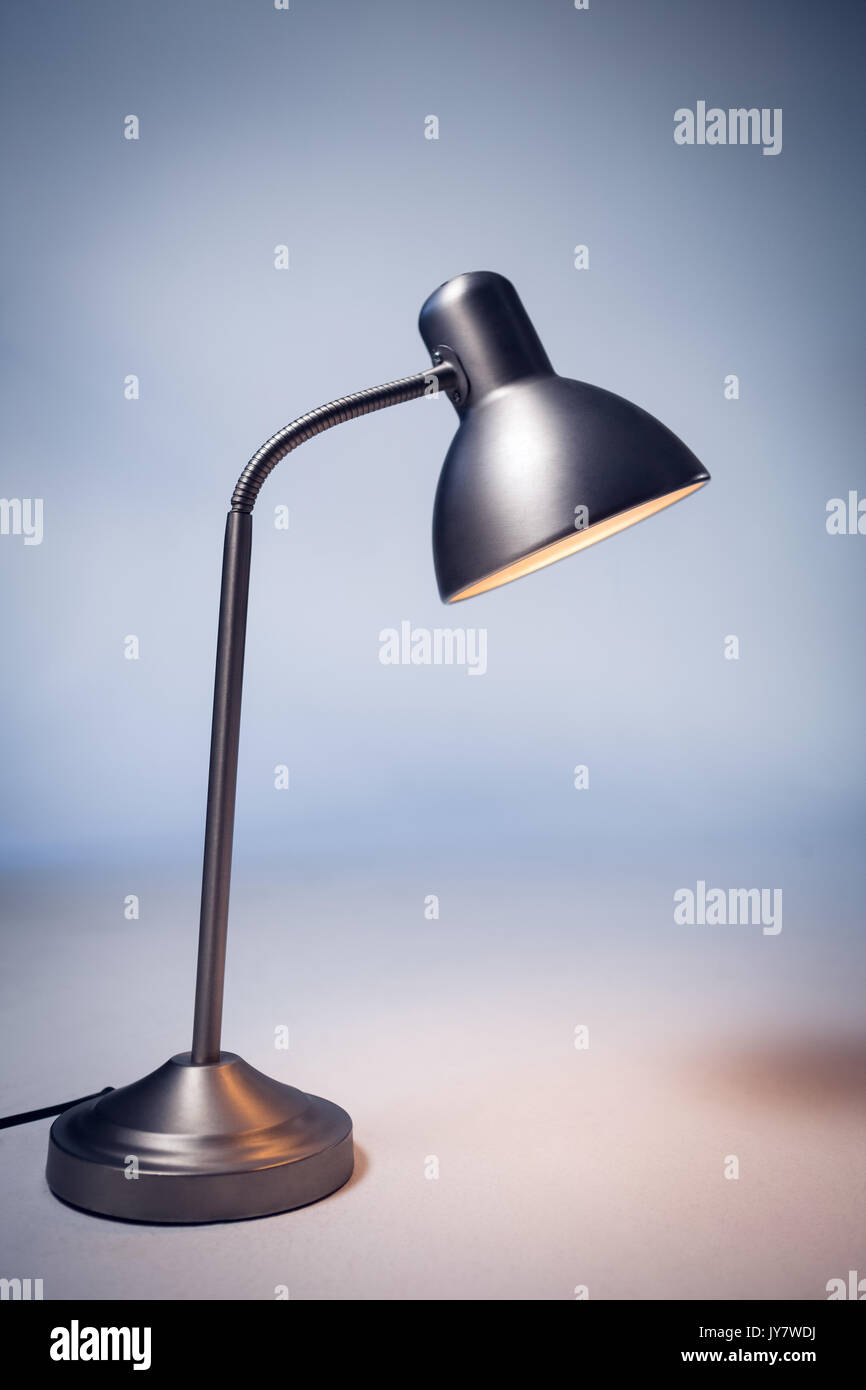 Close up of illuminated electric lamp on table by wall in office Stock Photo