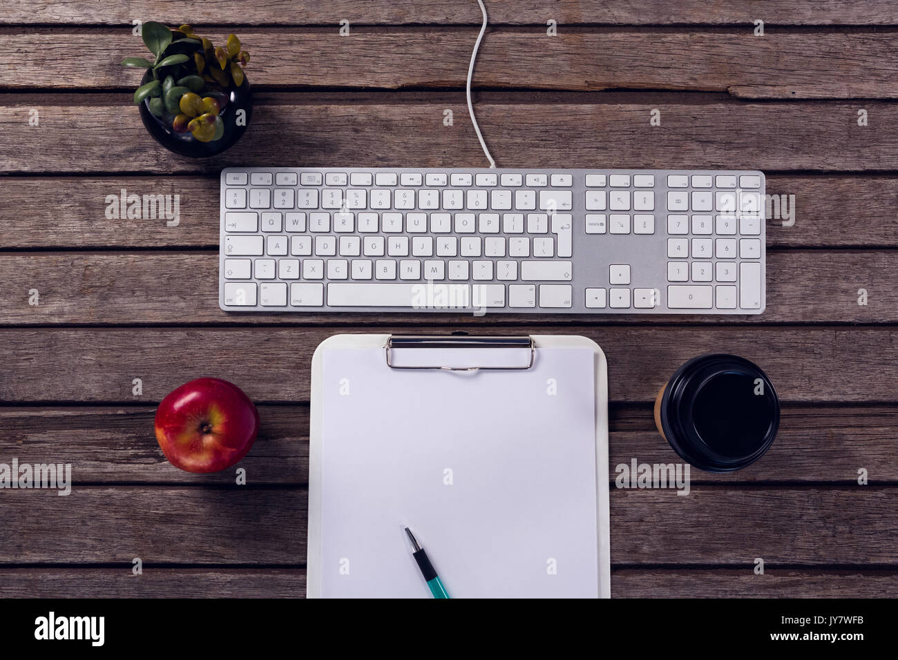 Overhead of keyboard, clipboard, apple, coffee cup and pot plant on wooden table Stock Photo Alamy