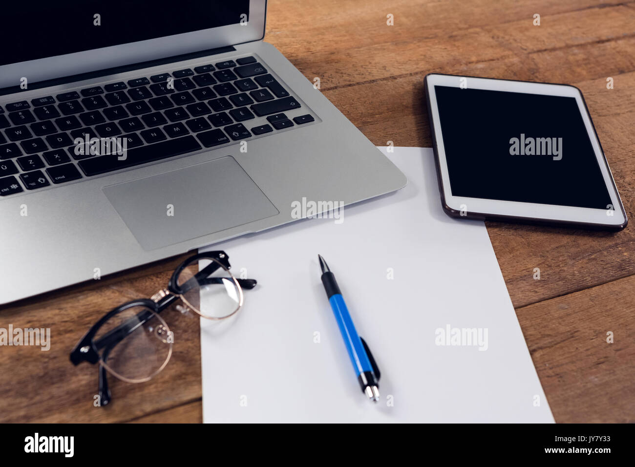 Close Up Of Digital Tablet Laptop Paper Pen And Spectacles On