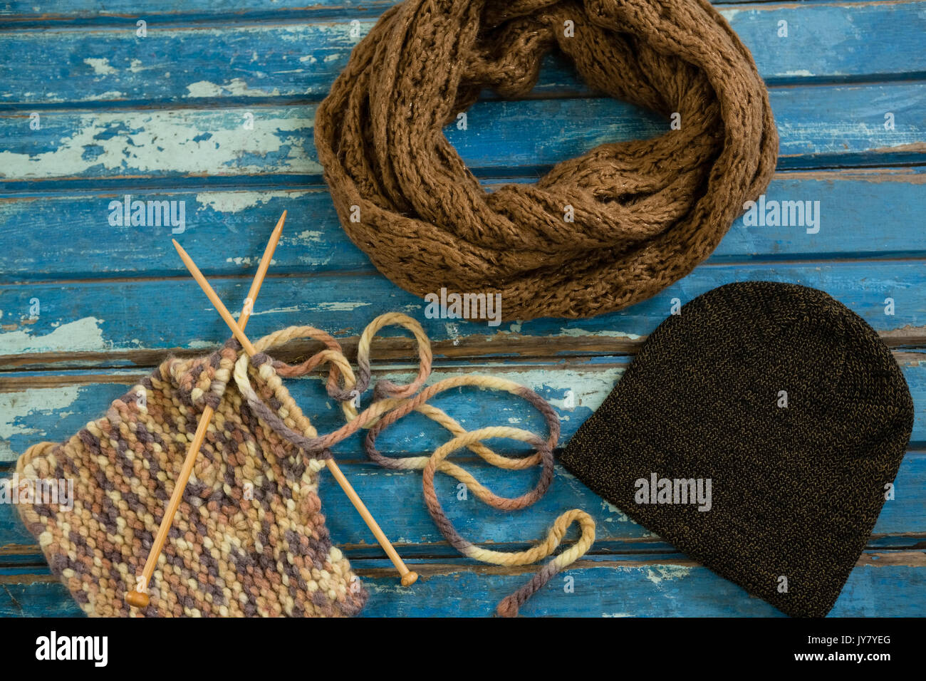 High angle view of muffler with knit hat and knitting needles on wooden table Stock Photo