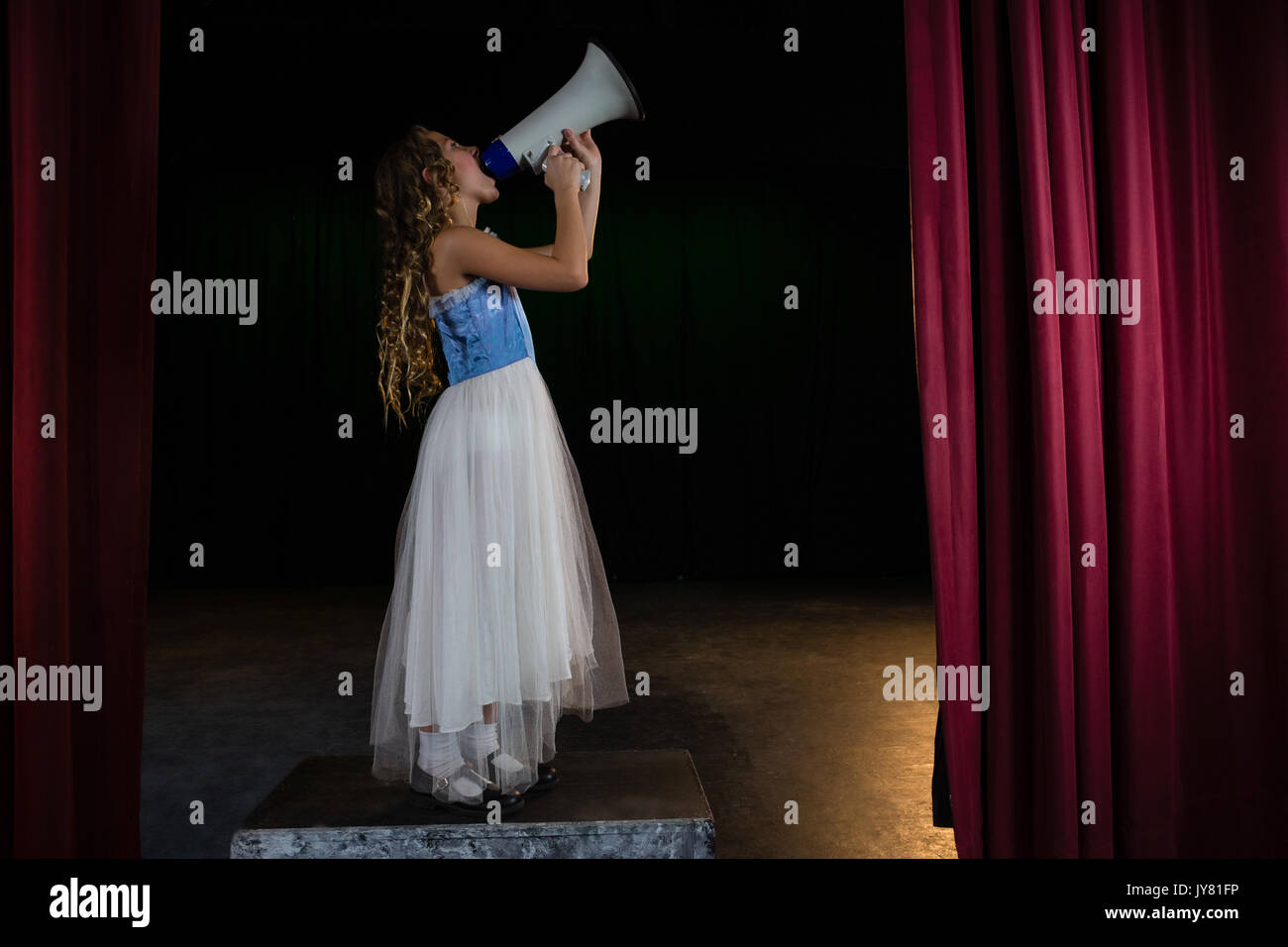 Female artist announcing on megaphone on stage in theatre Stock Photo ...