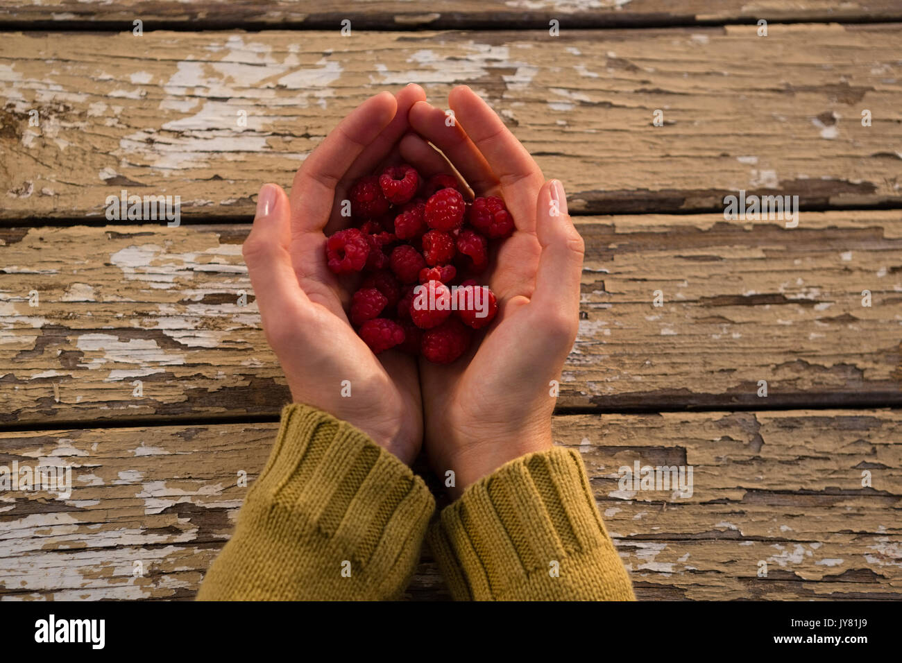 Overhead view of woman holding raspberries at table Stock Photo - Alamy