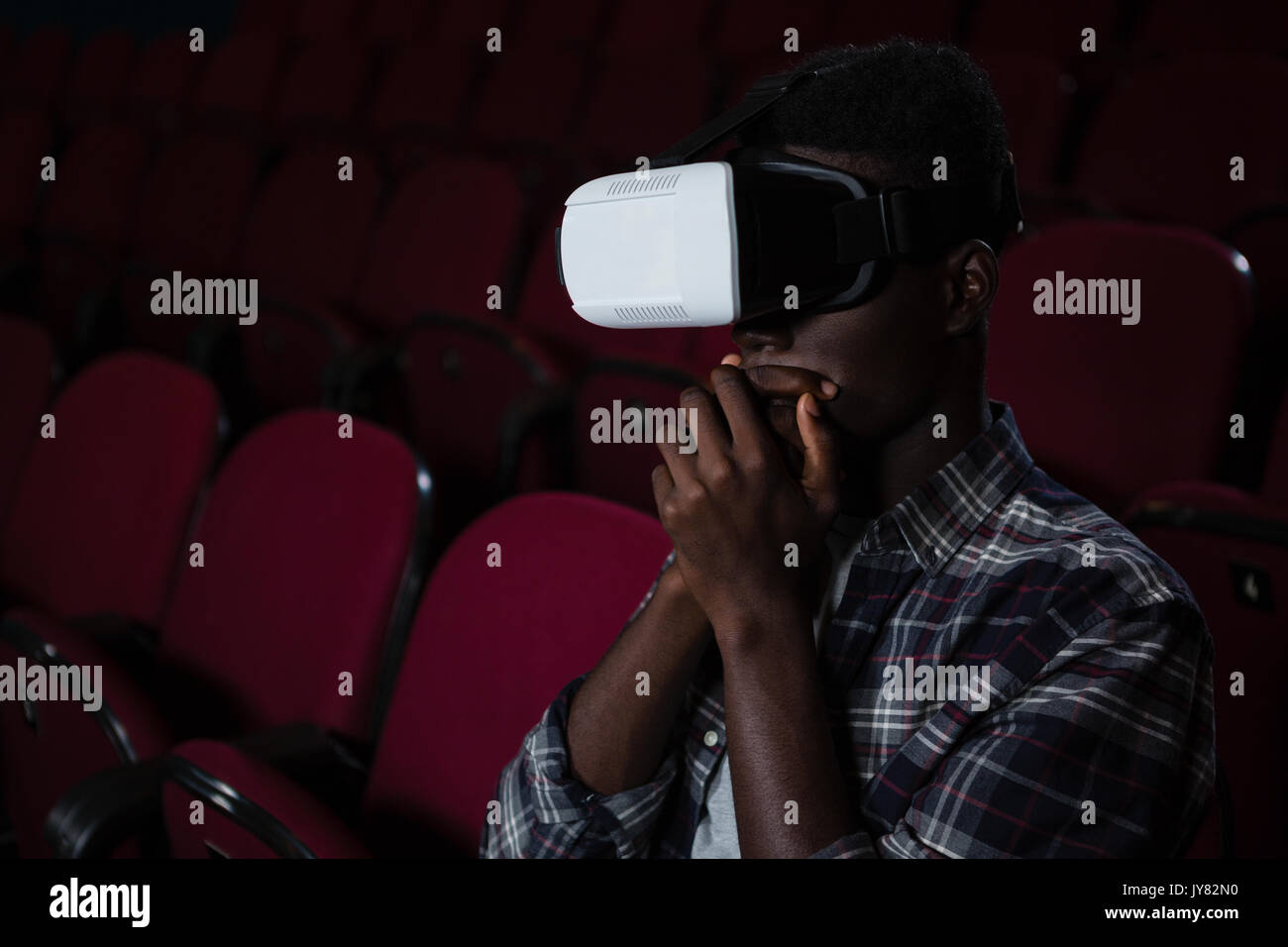 Man using virtual reality headset while watching movie in theatre Stock Photo