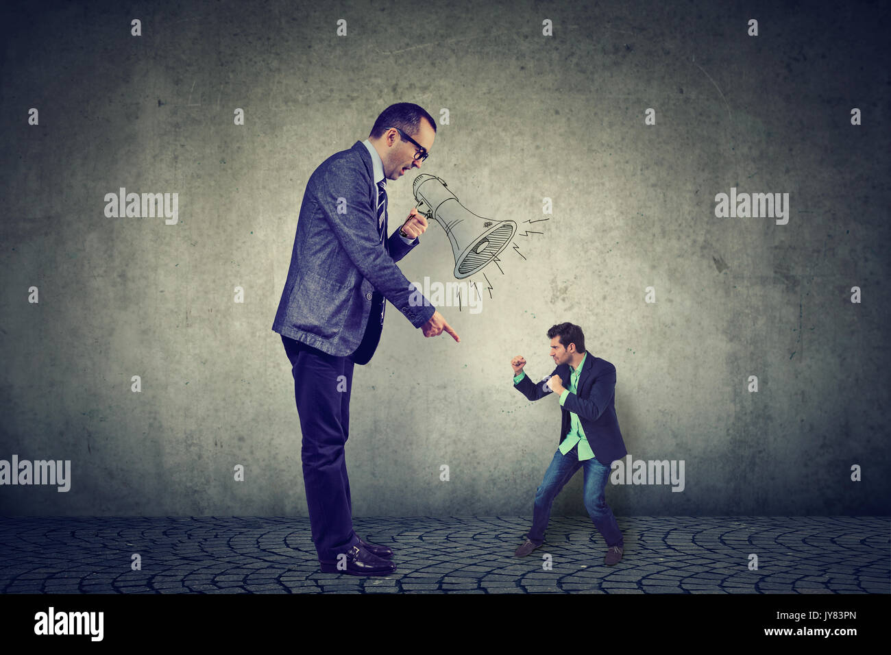 Man fighting against his big angry boss standing by gray wall background Stock Photo