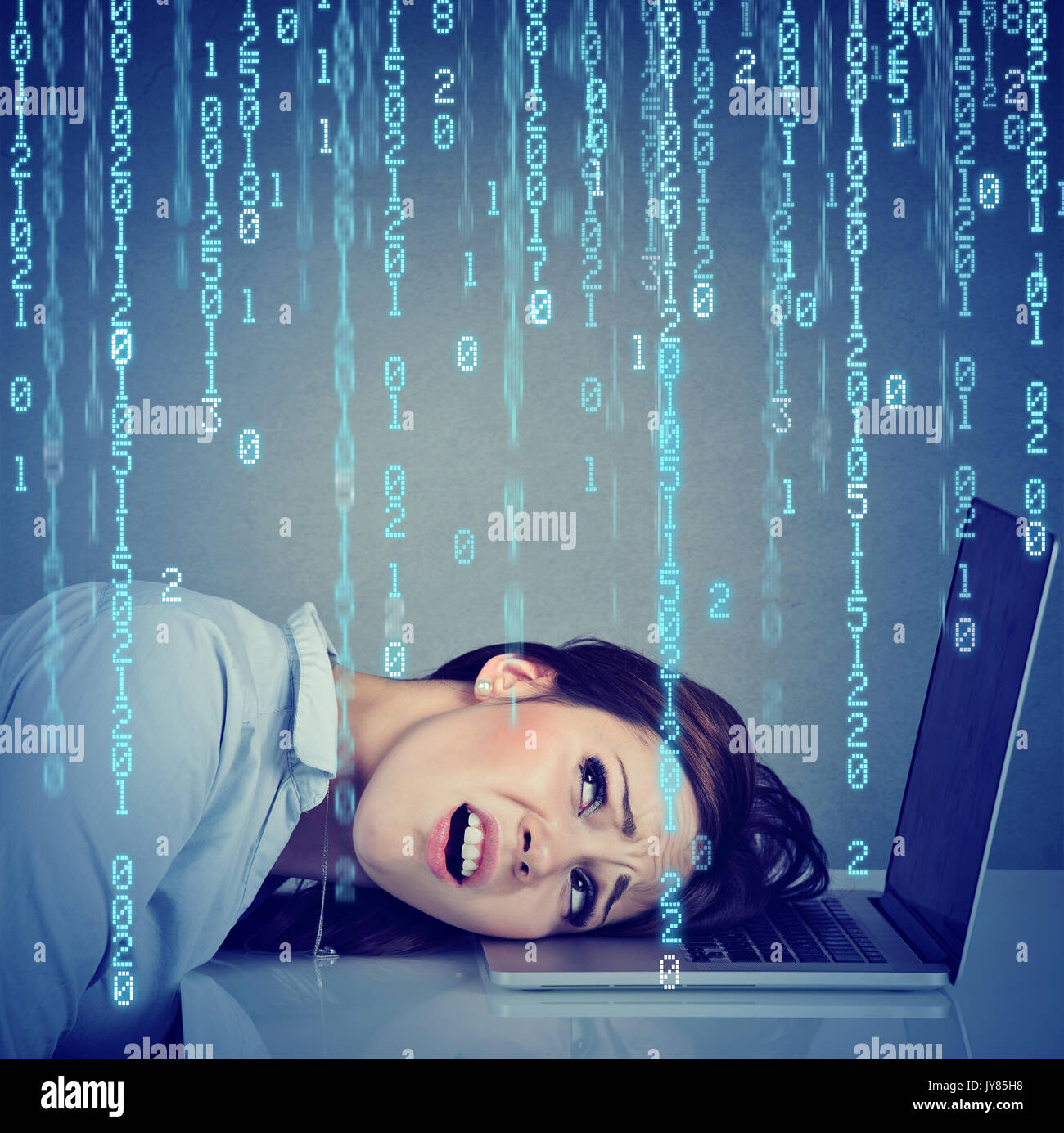 Desperate employee, stressed woman resting head on laptop with binary code falling down Stock Photo