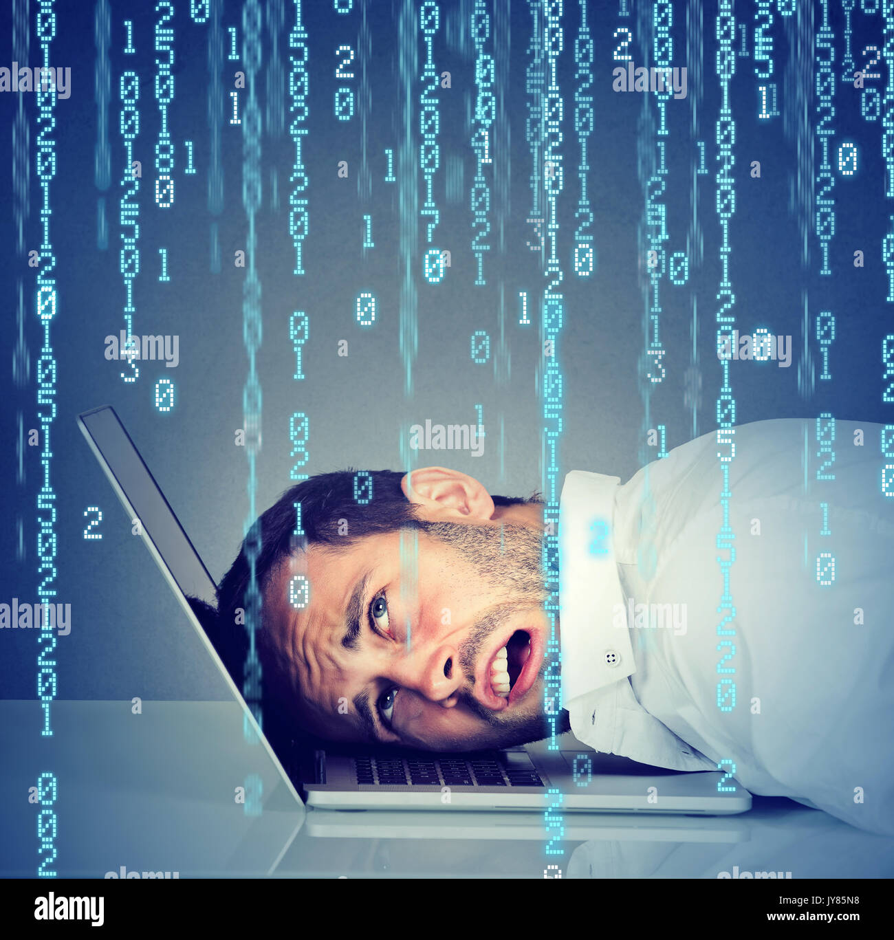 Desperate employee, stressed man resting head on laptop with binary code falling down Stock Photo