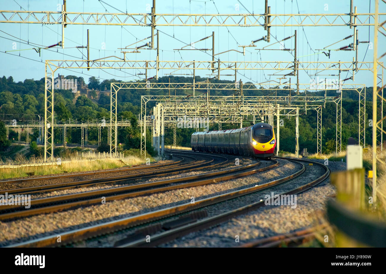 Class 390156 heads for Manchester Piccadilly with a service from London Euston as Merevale Hall, in the background overlooks the North Warwickshire co Stock Photo