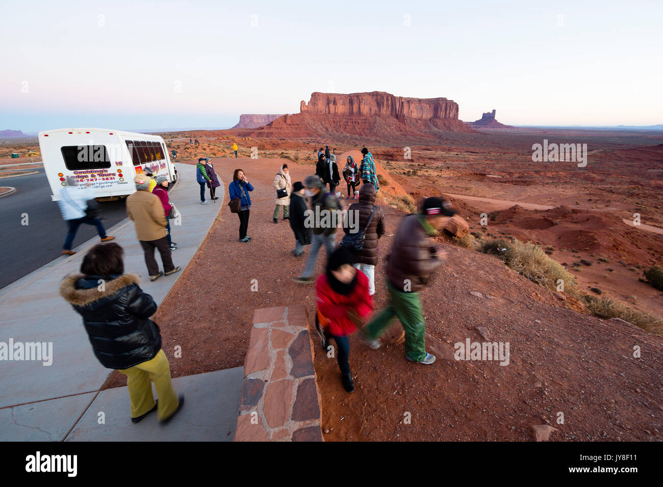 Monument Valley, Utah, USA. A group of Asian tourists walk at a viewpoint at Monument Valley near their tour bus during sunrise. Stock Photo