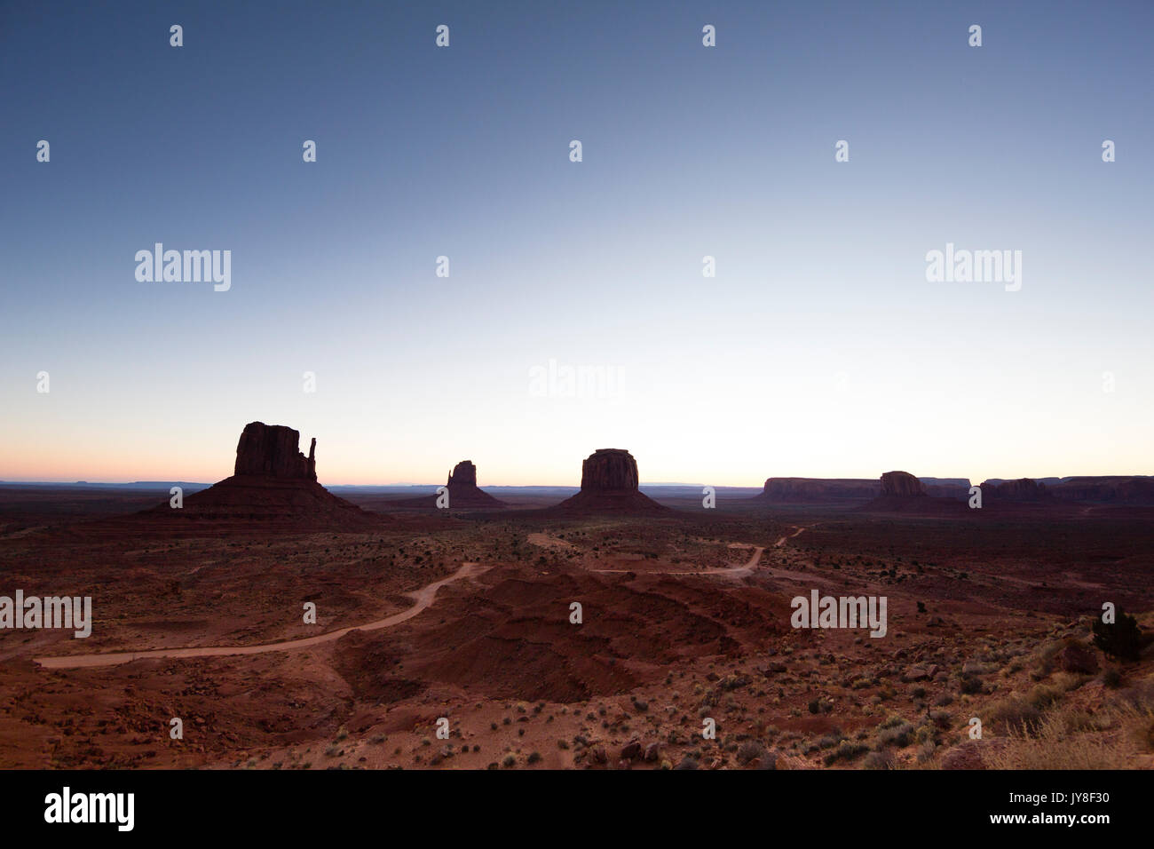 Monument Valley, Utah, USA. Pre-dawn light begins to spill over the horizon, lighting West and East Mitten Buttes. Stock Photo