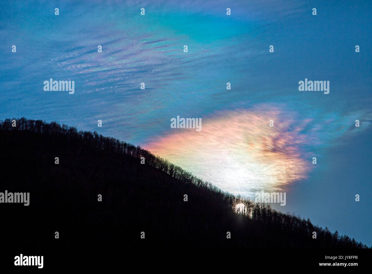 A lonely cloud with iridescence paints the sky with the colors of the rainbow Valtellina Lombardy Italy Europe Stock Photo