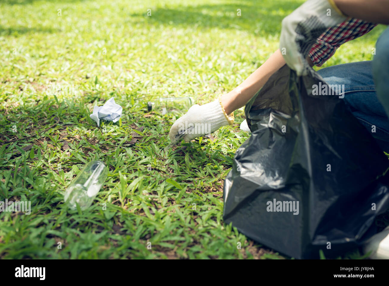 Young man crouching to waste and picking it up in bin bag Stock Photo