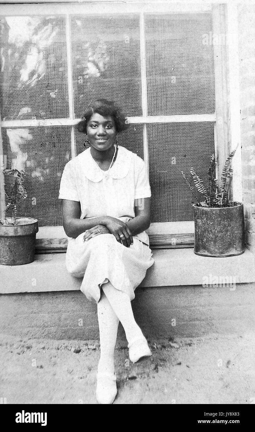 Full length portrait of a young African American woman, seated outside ...
