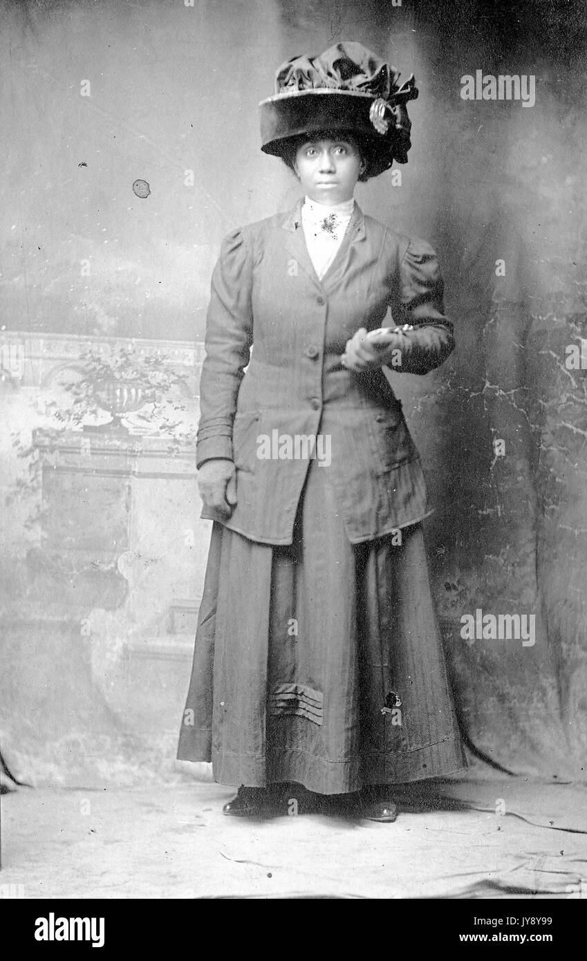 Full length portrait, African American woman; wearing long dress, large hat, neutral facial expression; Correspondence: 'Keep two to remember one while we are apart'; From Ellen G Wells to Miss Ethell Vamm, 1915. Stock Photo