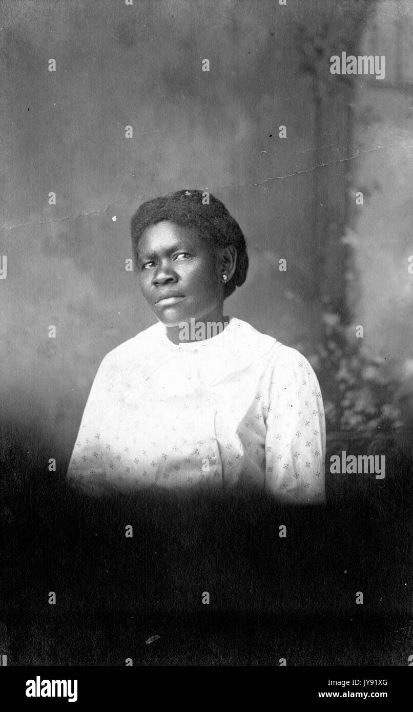 Studio portrait of mature African-American woman, the bottom half of the portrait overexposed and fading to black, 1930. Stock Photo