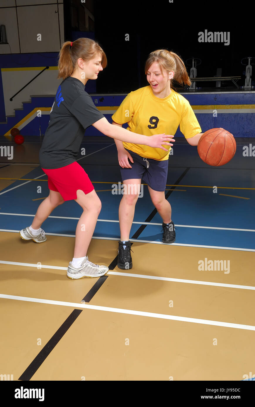 Two female basketball players scrimmage in school gym. Stock Photo