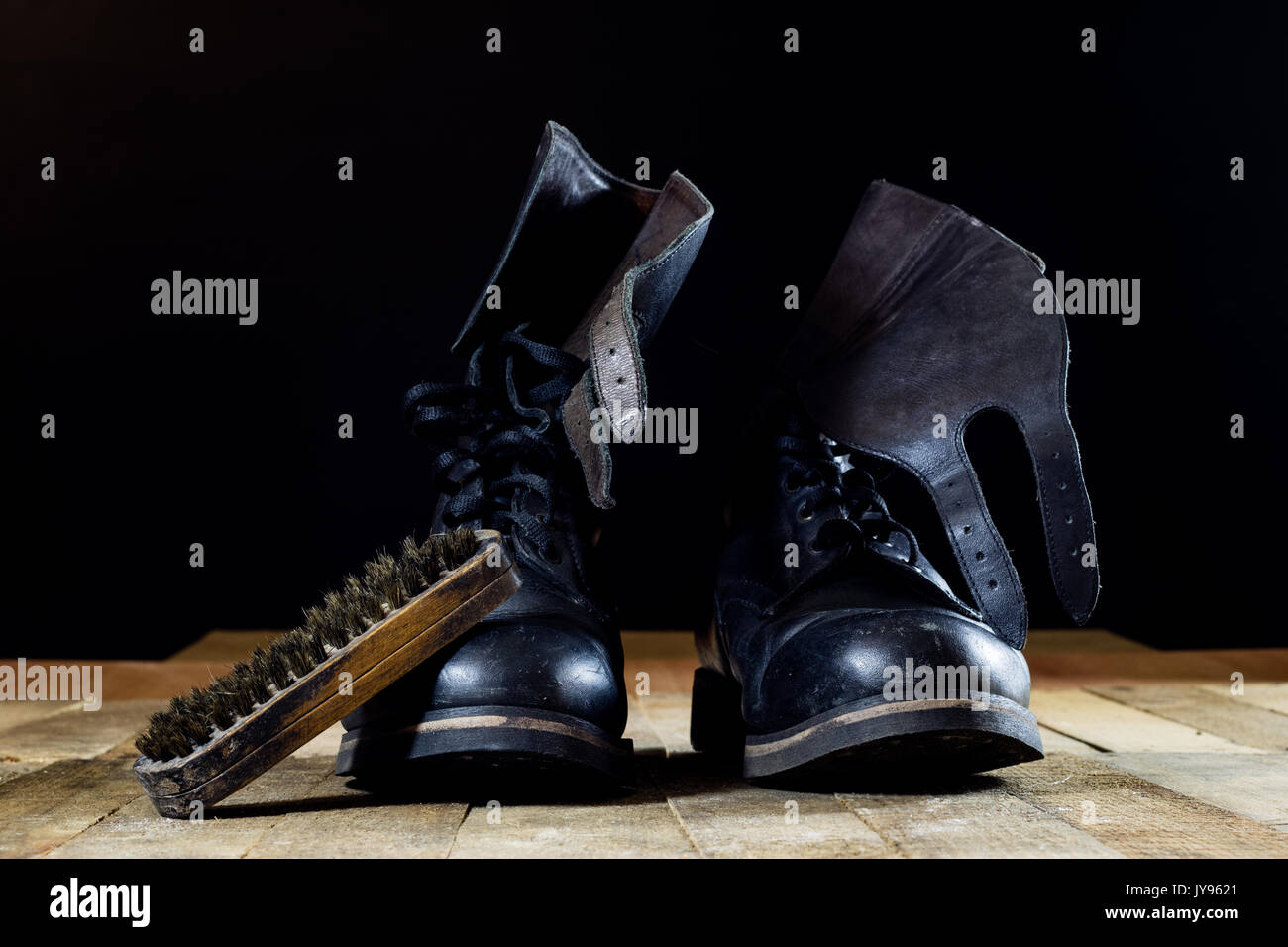 Old black Polish military boots on a wooden table. Black background