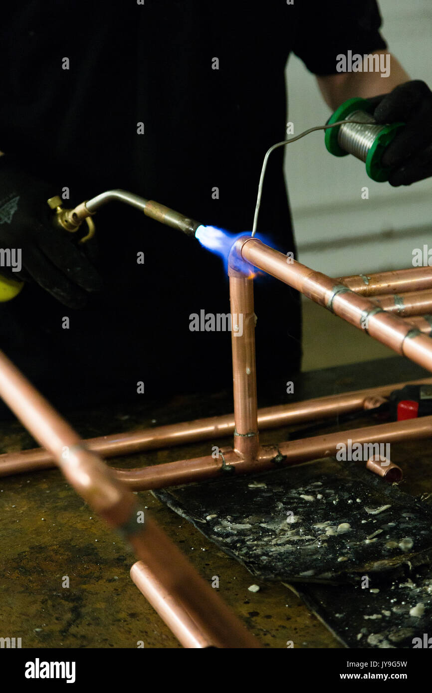 Essex, UK. A plumber uses a blowtorch to weld together a set of copper pipes. Stock Photo