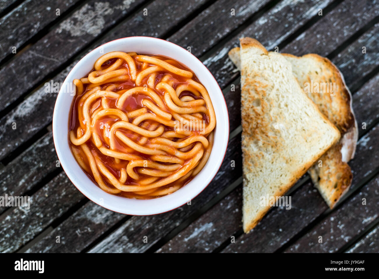 Bowl of Spaghetti in Tomato Sauce Against a Dark Weathered Table Top Stock Photo